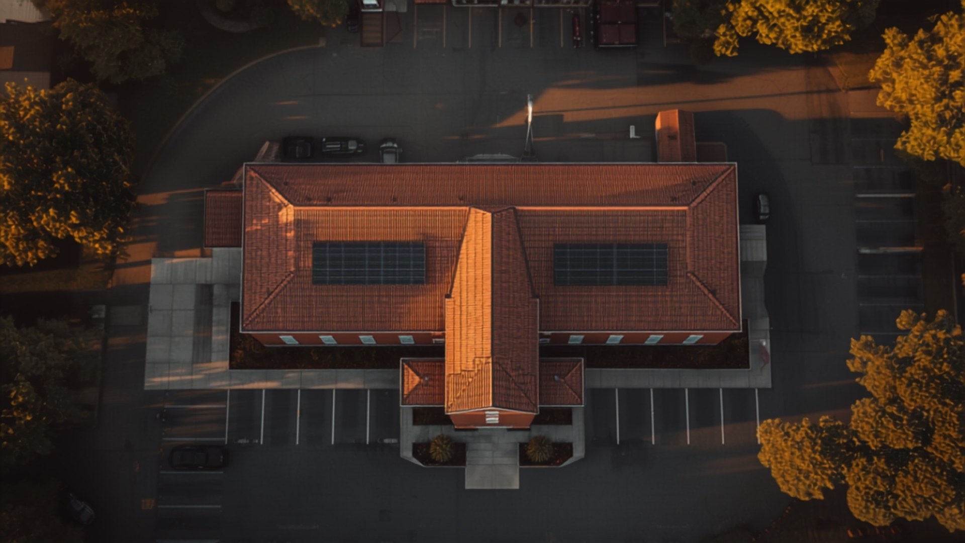 Aerial view at sunset of a church roof with solar panels and an empty parking lot